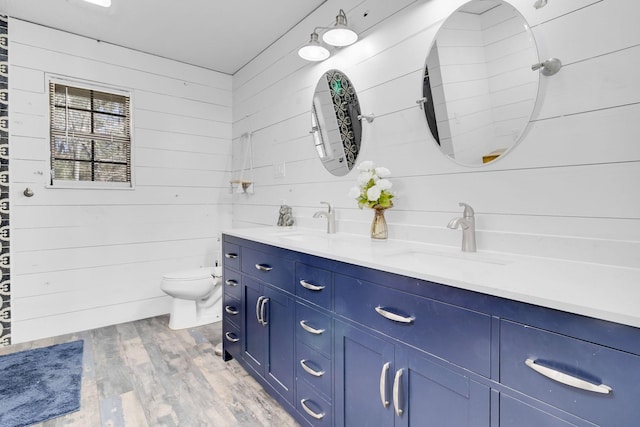 full bath with wood finished floors, toilet, double vanity, and a sink