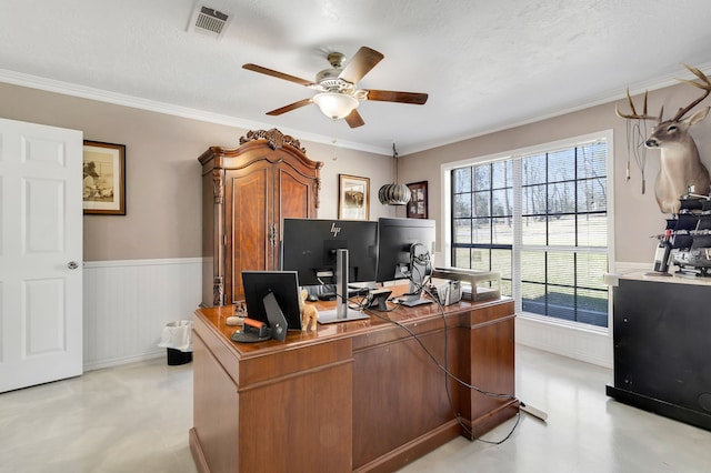 office space with ornamental molding, wainscoting, visible vents, and a ceiling fan