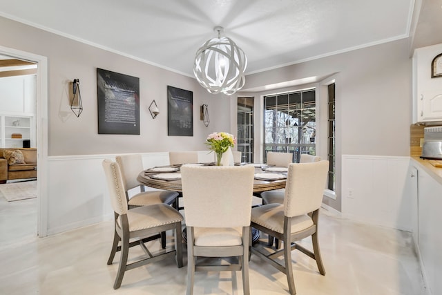 dining area featuring a wainscoted wall, finished concrete floors, crown molding, and an inviting chandelier