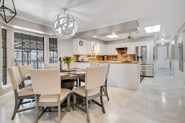 dining area with crown molding, a skylight, a chandelier, and concrete floors