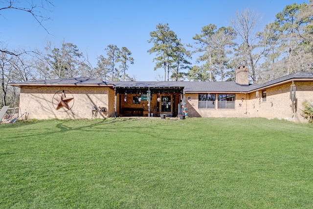 back of property featuring brick siding, a lawn, and a chimney