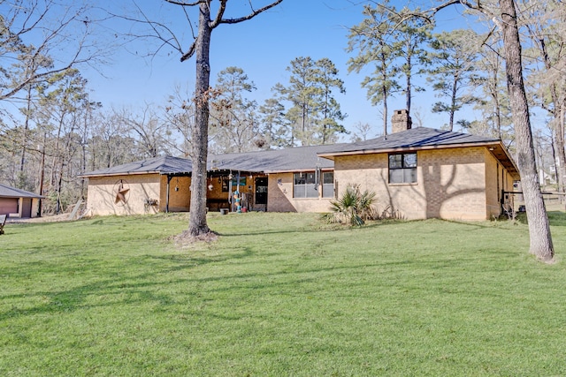 rear view of property with brick siding, a chimney, and a yard