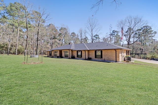 view of front of home featuring a front lawn, roof with shingles, and brick siding