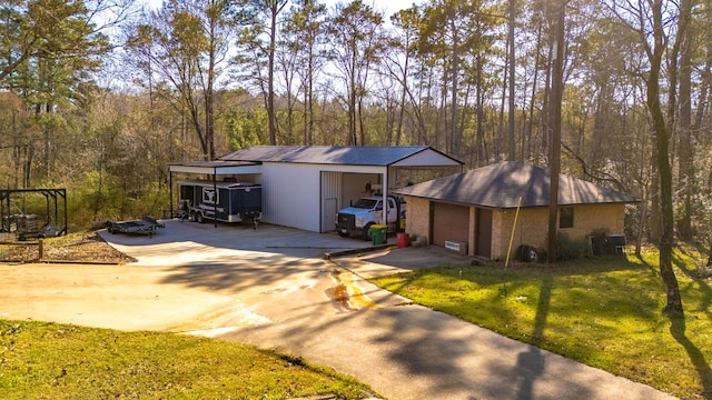 exterior space featuring concrete driveway, an outdoor structure, and a view of trees