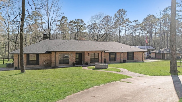 single story home featuring a chimney, brick siding, a shingled roof, and a front yard