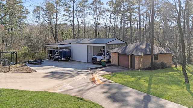 view of front of house with a garage, an outdoor structure, a front yard, and concrete driveway