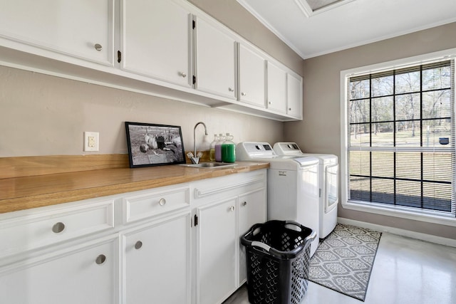 laundry room featuring a sink, cabinet space, separate washer and dryer, baseboards, and ornamental molding