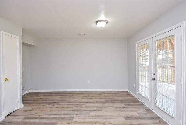 empty room with light wood finished floors, baseboards, visible vents, and french doors