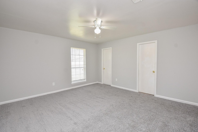 carpeted spare room featuring ceiling fan and baseboards