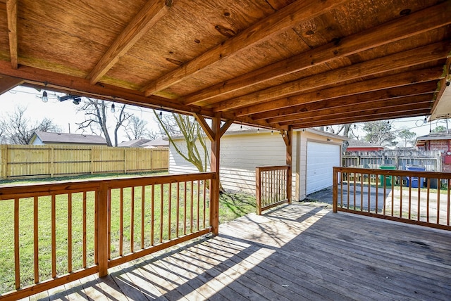 wooden deck with a garage, fence, an outdoor structure, and a lawn