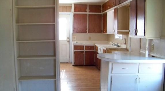 kitchen with a peninsula, light wood-type flooring, open shelves, and light countertops