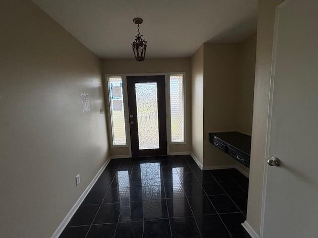 foyer entrance featuring dark tile patterned flooring and baseboards