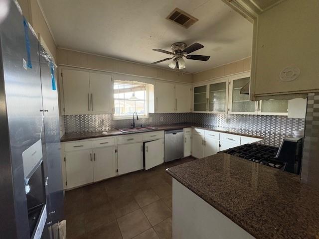 kitchen featuring visible vents, decorative backsplash, appliances with stainless steel finishes, white cabinetry, and a sink