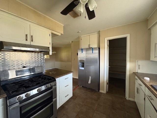 kitchen featuring under cabinet range hood, white cabinets, appliances with stainless steel finishes, backsplash, and dark countertops