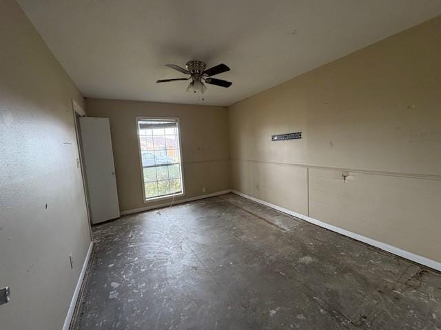 unfurnished room with a ceiling fan and baseboards