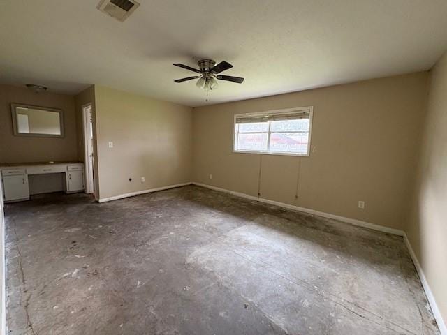 spare room with baseboards, visible vents, built in study area, ceiling fan, and unfinished concrete floors