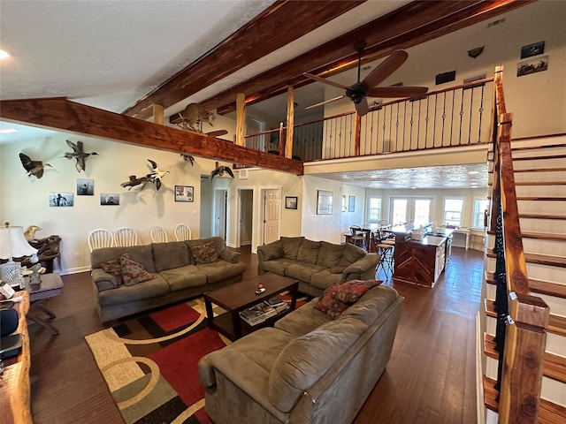 living area with dark wood finished floors, ceiling fan, stairs, high vaulted ceiling, and beam ceiling