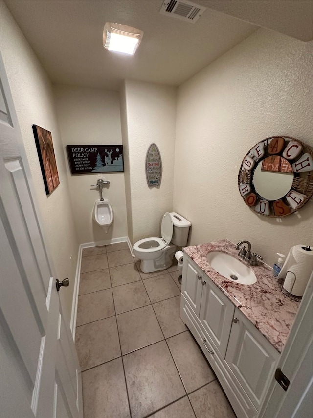 bathroom featuring toilet, vanity, baseboards, visible vents, and tile patterned floors