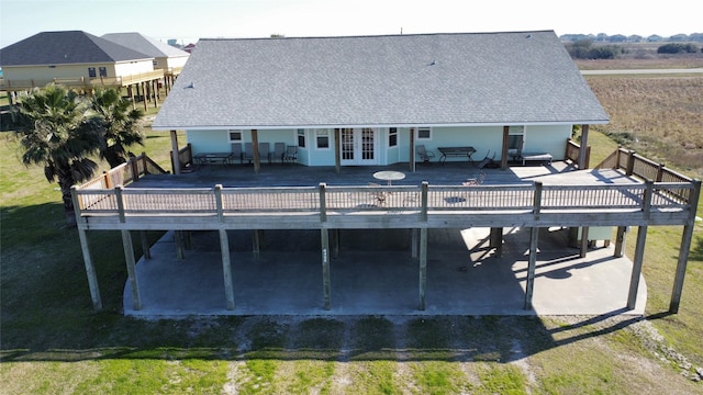 back of house with driveway, a lawn, french doors, roof with shingles, and a wooden deck