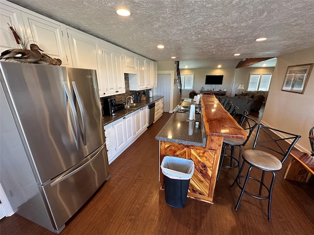 kitchen with white cabinetry, dark wood-style flooring, stainless steel appliances, and a sink