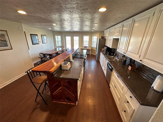 kitchen with stainless steel appliances, dark wood-style flooring, a sink, white cabinets, and french doors