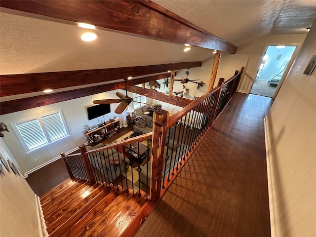 stairway with vaulted ceiling with beams, a textured ceiling, plenty of natural light, and hardwood / wood-style flooring