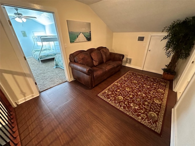 living room featuring dark wood-type flooring, visible vents, and vaulted ceiling