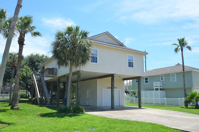 rear view of property featuring fence, a yard, driveway, stairway, and a carport