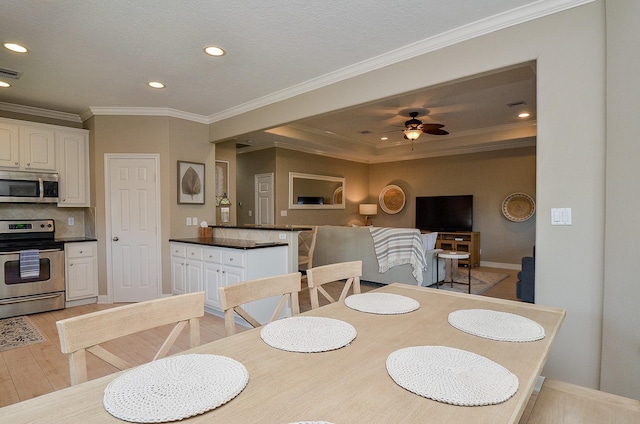 dining room with light wood-type flooring, ceiling fan, ornamental molding, and recessed lighting