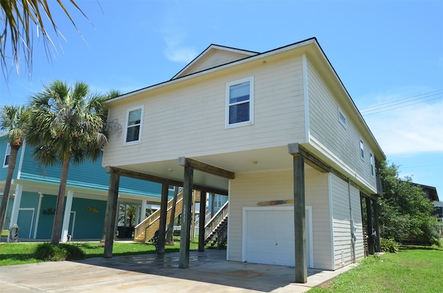 view of front facade with concrete driveway, an attached garage, a front yard, a carport, and stairs