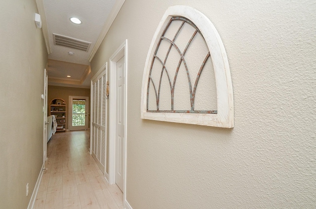 hall with a textured wall, recessed lighting, visible vents, light wood-style floors, and crown molding