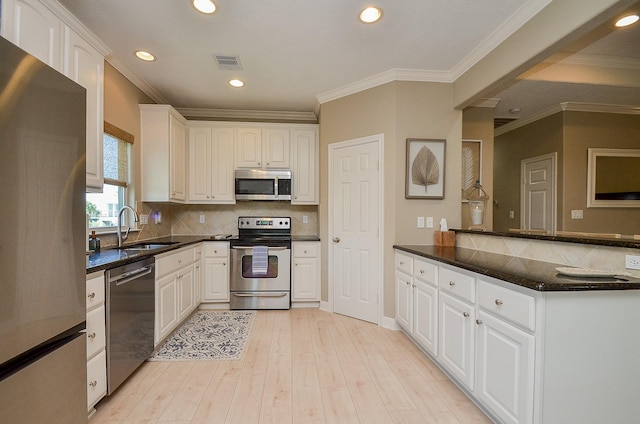 kitchen with visible vents, appliances with stainless steel finishes, white cabinetry, a sink, and light wood-type flooring