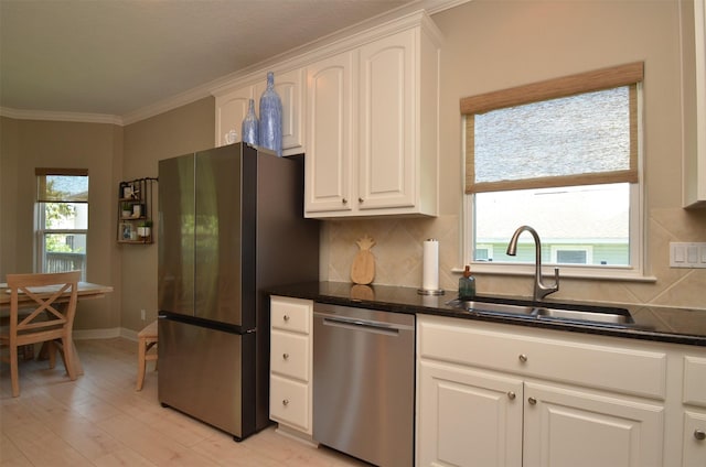 kitchen with a sink, ornamental molding, appliances with stainless steel finishes, a wealth of natural light, and tasteful backsplash