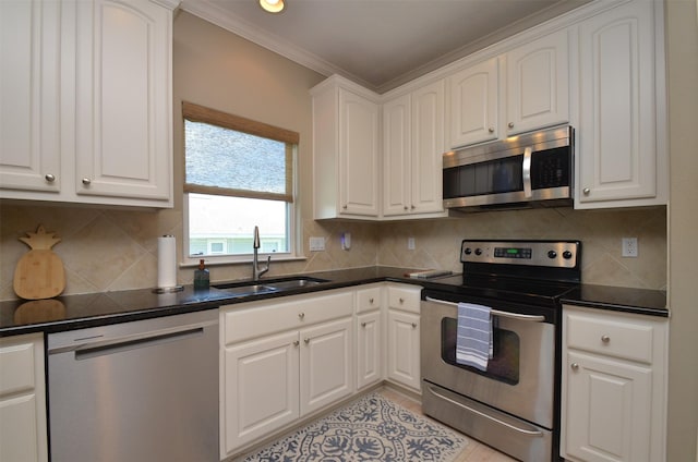 kitchen featuring dark countertops, white cabinetry, appliances with stainless steel finishes, and a sink