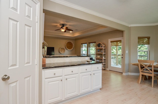 kitchen with light wood-style flooring, ornamental molding, white cabinets, and baseboards