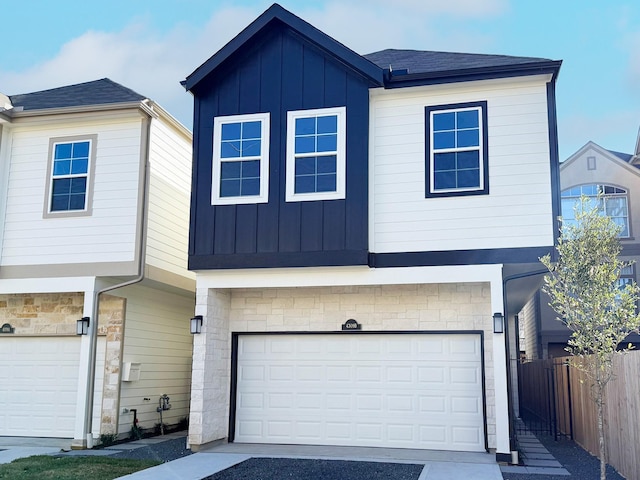 view of front of property with stone siding, board and batten siding, an attached garage, and fence