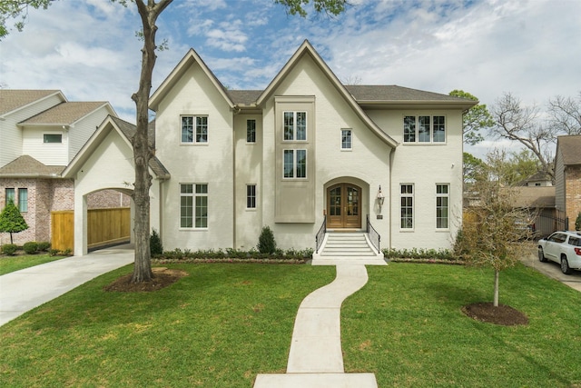 view of front of home featuring driveway, a front yard, fence, and french doors