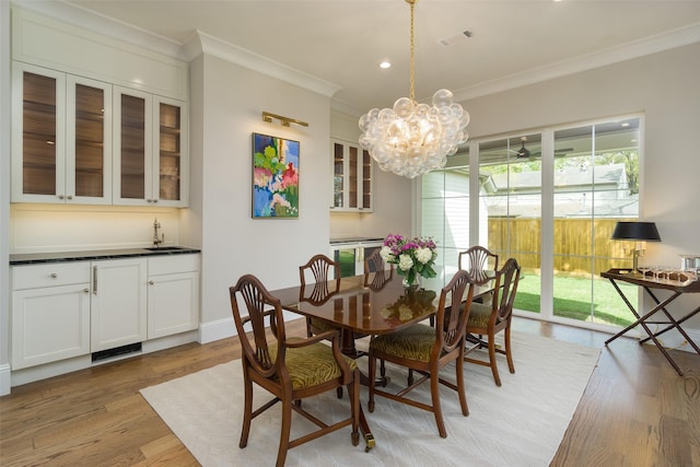 dining area with visible vents, light wood-type flooring, an inviting chandelier, and crown molding