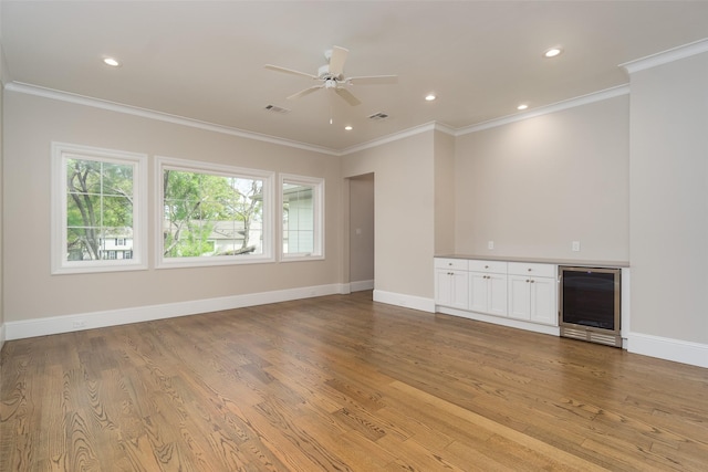 unfurnished living room featuring beverage cooler, light wood-type flooring, visible vents, and crown molding