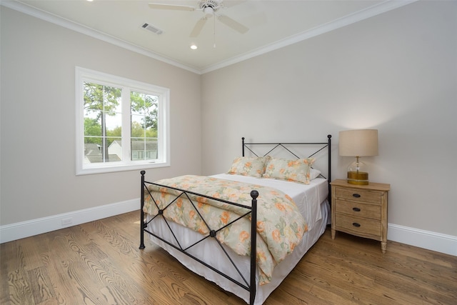 bedroom with baseboards, wood finished floors, visible vents, and crown molding