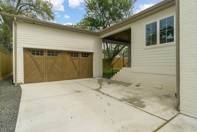 garage featuring concrete driveway and fence