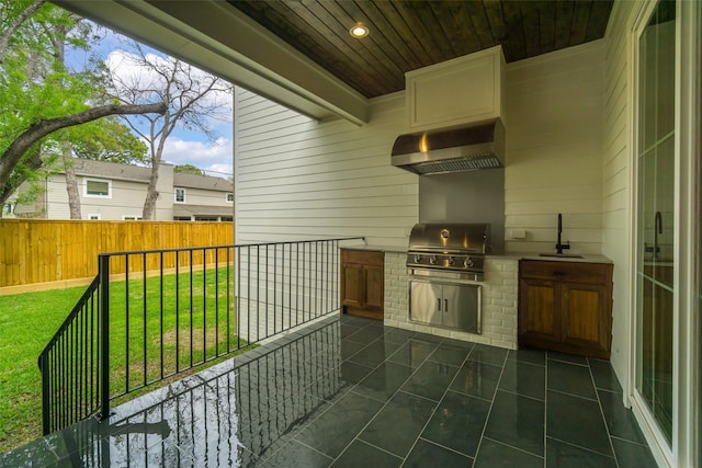 view of patio with a sink, fence, grilling area, and exterior kitchen