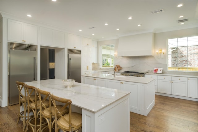 kitchen featuring a center island, stainless steel built in refrigerator, visible vents, and custom exhaust hood