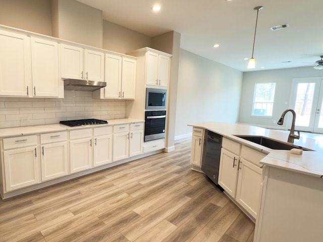 kitchen featuring visible vents, backsplash, a sink, under cabinet range hood, and black appliances