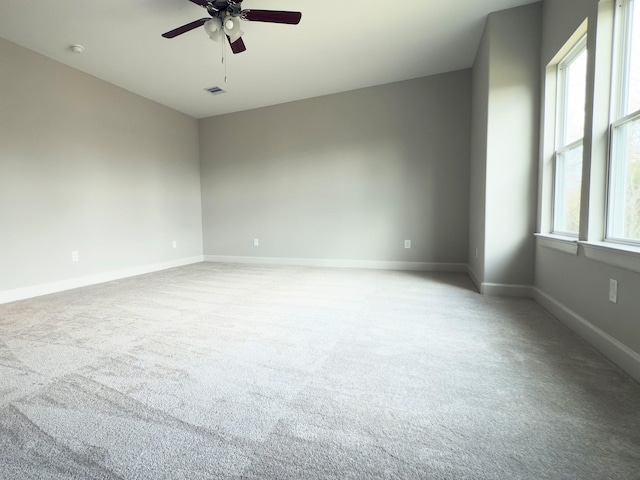 empty room featuring baseboards, ceiling fan, visible vents, and light colored carpet