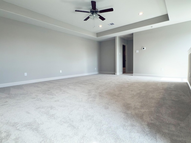 empty room featuring visible vents, baseboards, a raised ceiling, ceiling fan, and carpet