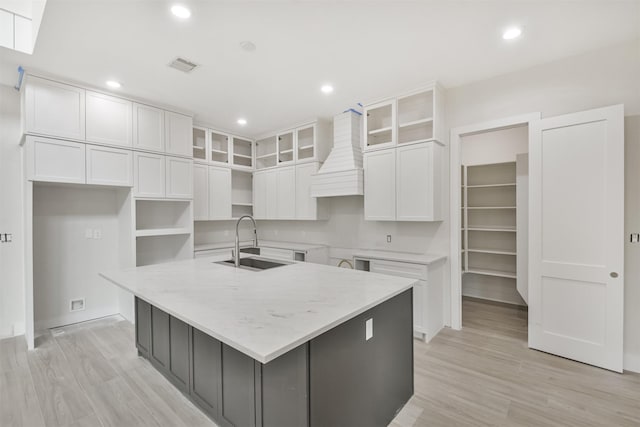 kitchen with light wood-style flooring, a sink, visible vents, a large island, and custom range hood