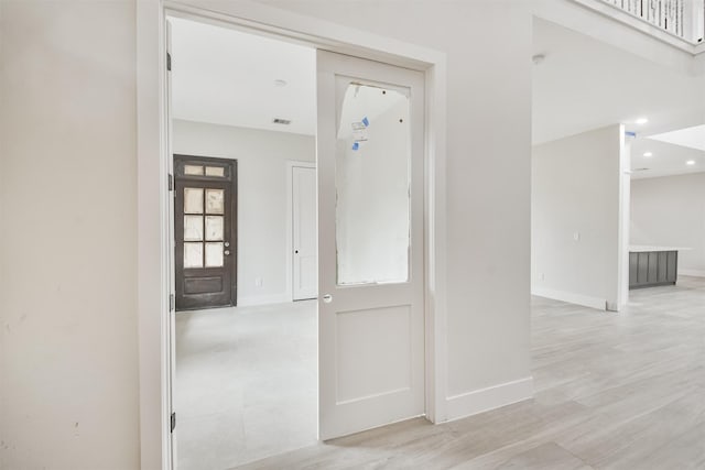 hall with light wood-type flooring, visible vents, baseboards, and recessed lighting