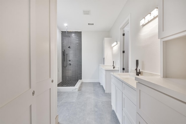 full bath featuring a sink, two vanities, visible vents, baseboards, and a stall shower