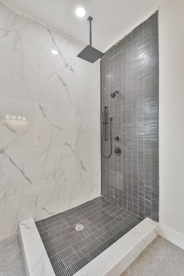 full bath featuring a tile shower and baseboards